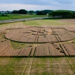 푸른 초원 위에 크롭 서클(Crop Circle)의 기하학적인 문양의 모습이 보인다